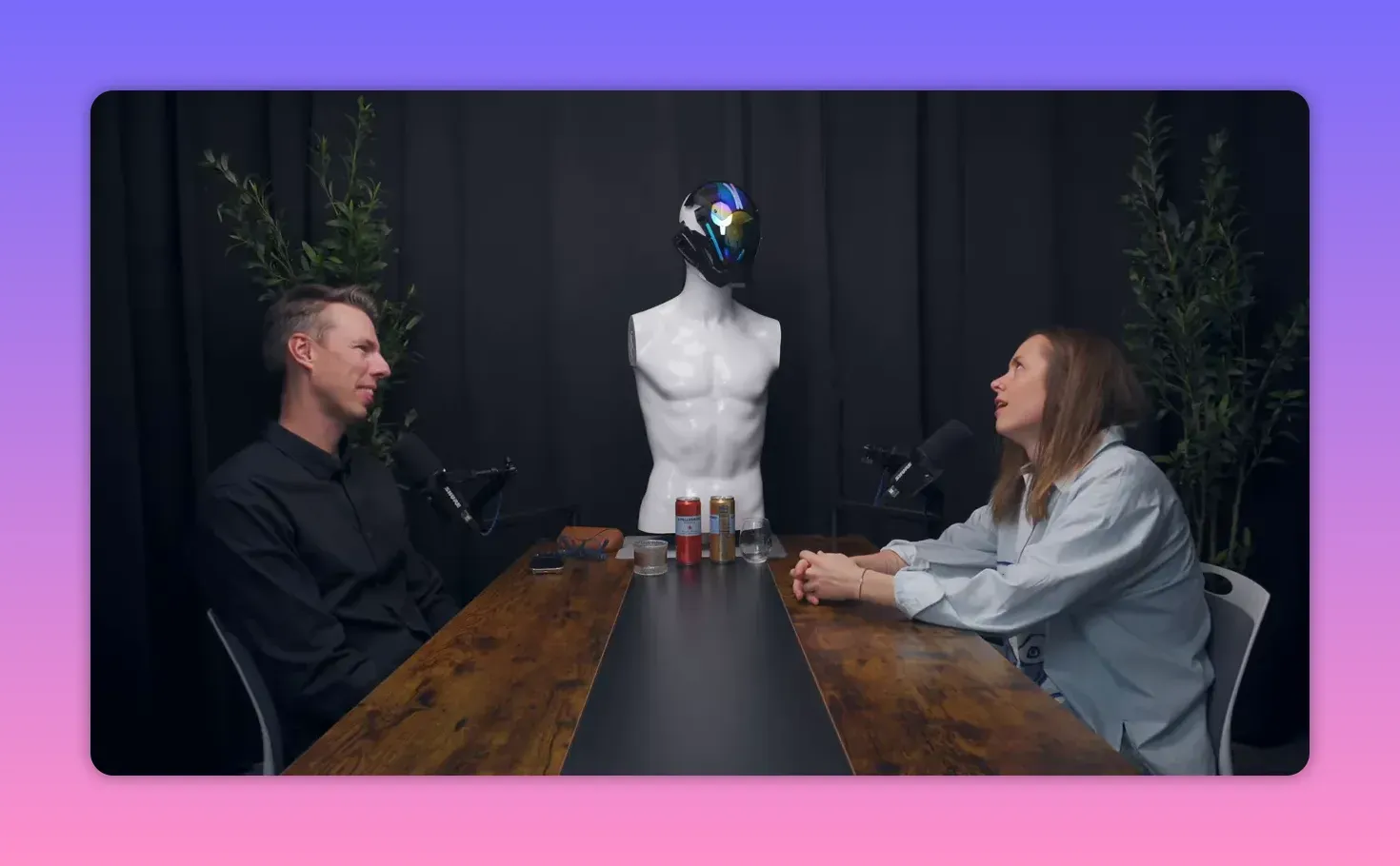 Широкий план: ведущий и Елена за столом, Елена смотрит вверх в задумчивости