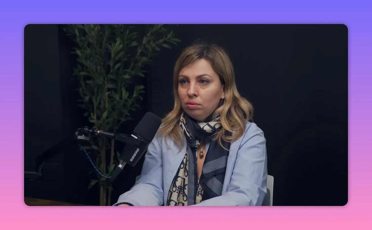 Чёткий средний план женщины в студии у микрофона: концентрированное, объясняющее выражение лица